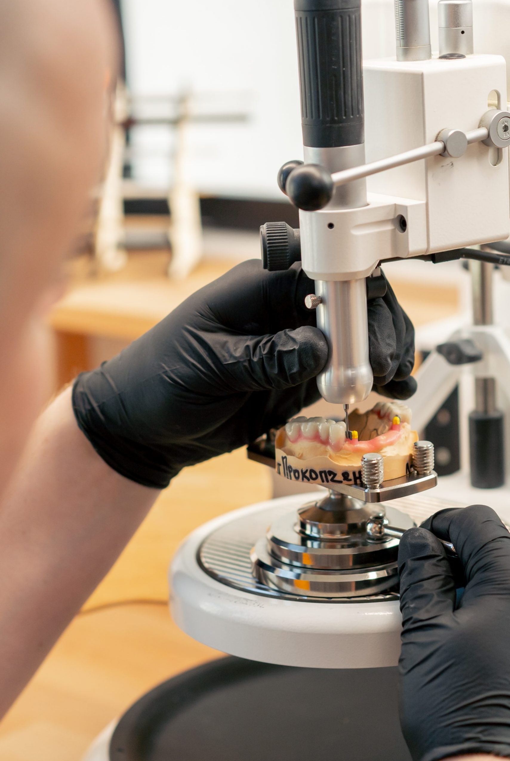 close up professional laboratory for the production of dental protoses veneers and crowns a specialist adjusts a crown to the shape of a person's jaw gums professional equipment